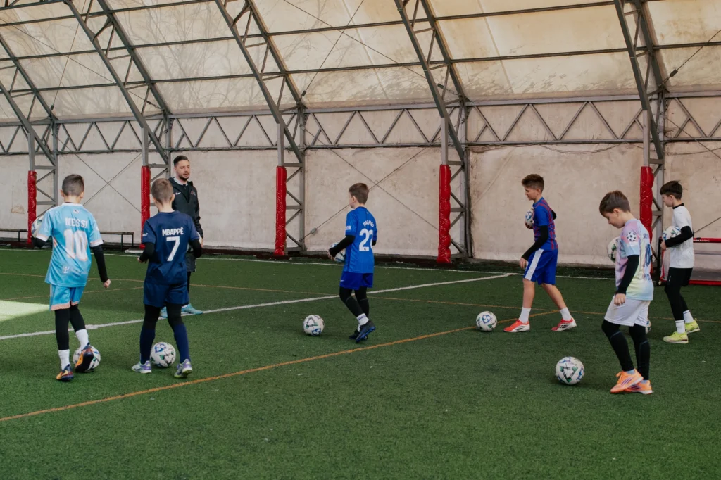 Juniori la antrenament de fotbal în sală, fiecare cu mingea lui