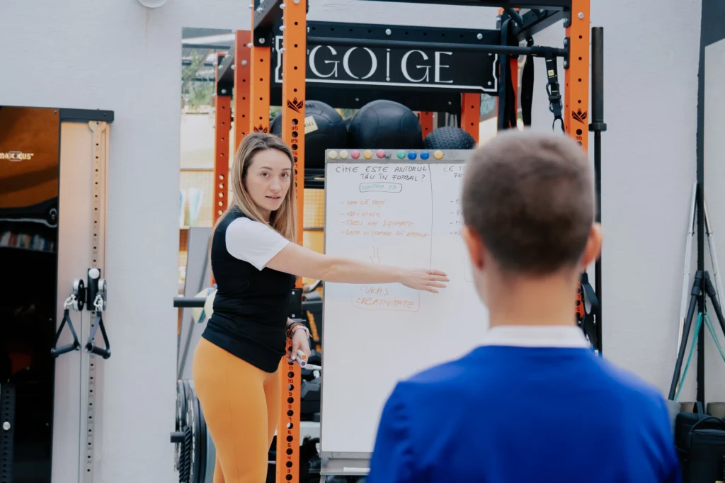 Coach GOGE explicând obiectivele pe tablă unui sportiv junior